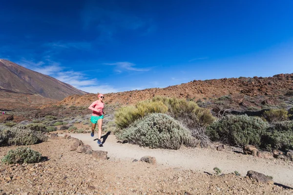 Mujer corriendo en las montañas en el soleado día de verano — Foto de Stock