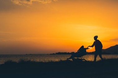 Anne annelik zevk bebek arabası ile bir sahilde yürüyüş