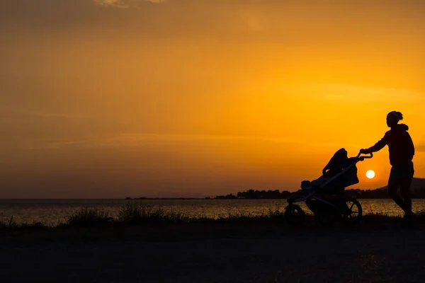 Mor promenader på stranden med barnvagn njuter av moderskap — Stockfoto