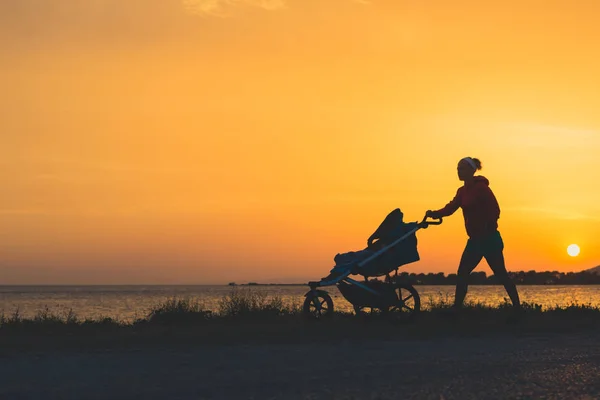 Мати гуляє на пляжі з коляскою, насолоджуючись материнством — стокове фото