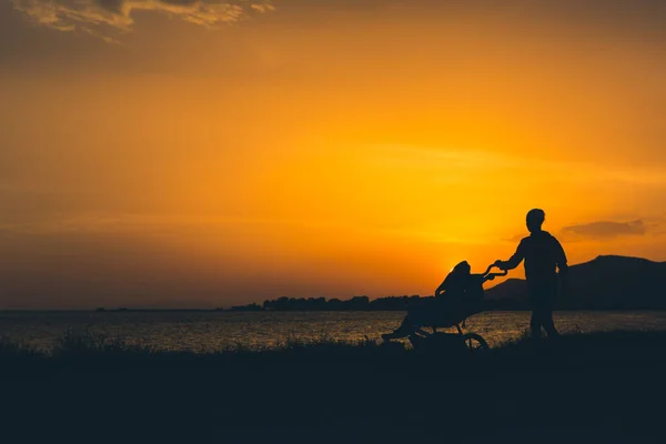 Mãe andando em uma praia com carrinho desfrutando maternidade — Fotografia de Stock