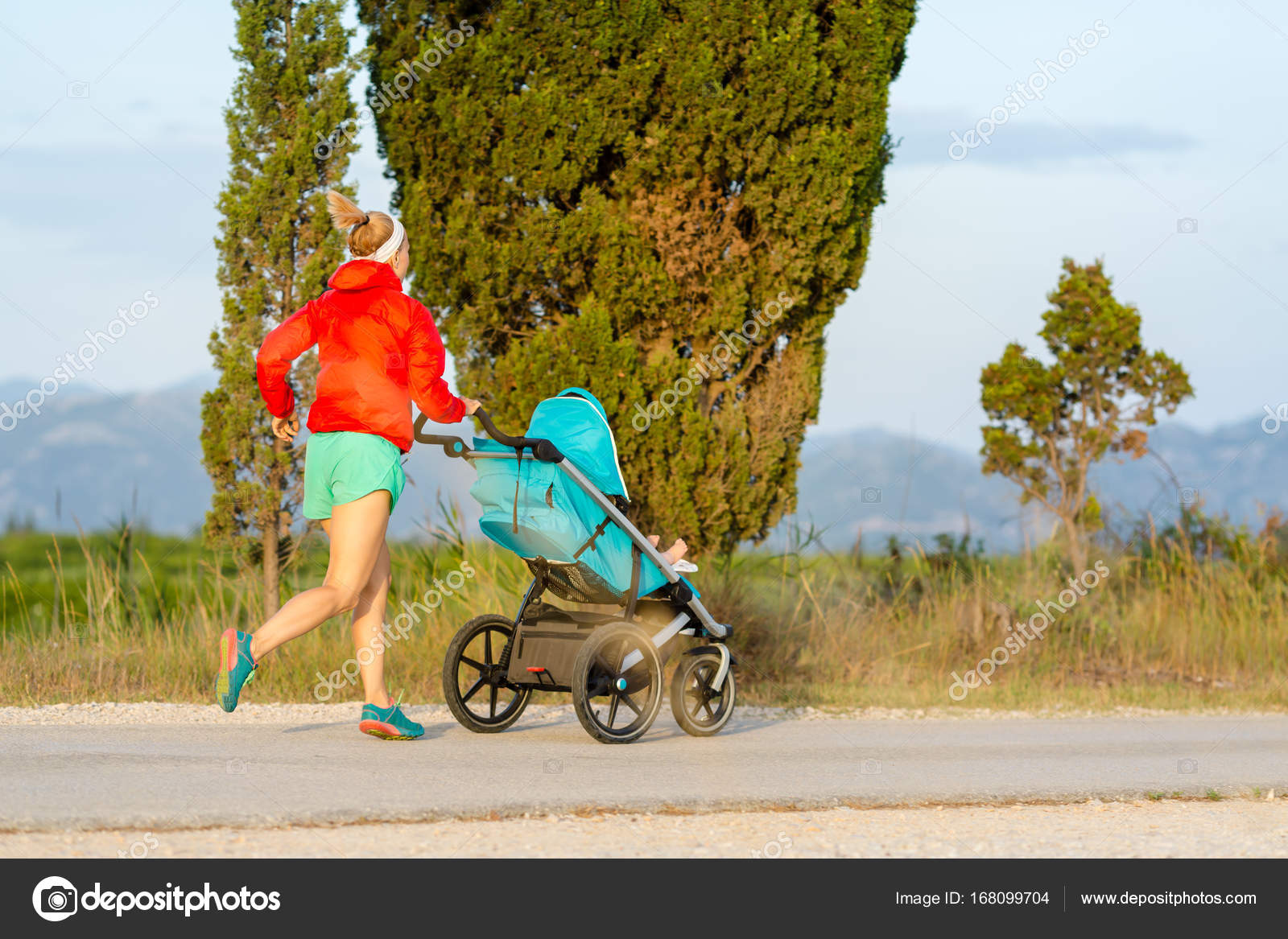 Running mother with stroller enjoying motherhood at sunset lands