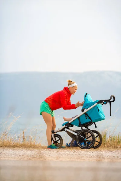 Madre con cochecito disfrutando de la maternidad al atardecer — Foto de Stock