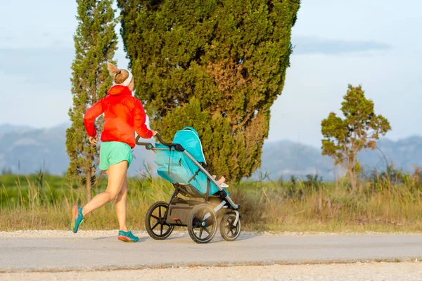 Madre corriendo con cochecito disfrutando de la maternidad en las tierras del atardecer — Foto de Stock