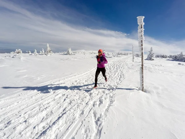 Mujer corriendo en el sendero de invierno, nieve y montañas blancas —  Fotos de Stock