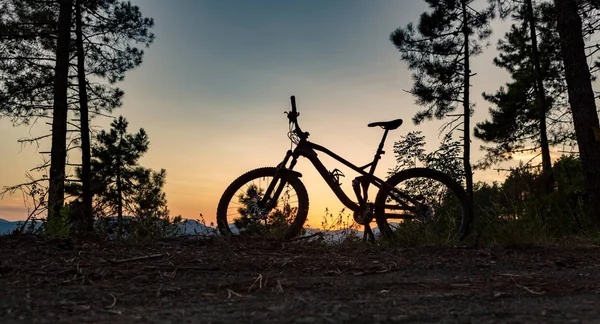 Mountain bike naplemente sziluett erdei ösvényen, inspiráló földek — Stock Fotó