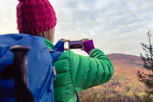 Mulher caminhando com mochila tirando foto com smartphone — Fotografia de Stock