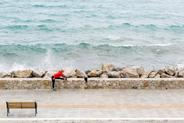 Женщина занимается спортом и бегает по городской улице, смотрит на море — стоковое фото