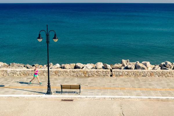 Kvinna som jogging på ort gata på seaside — Stockfoto