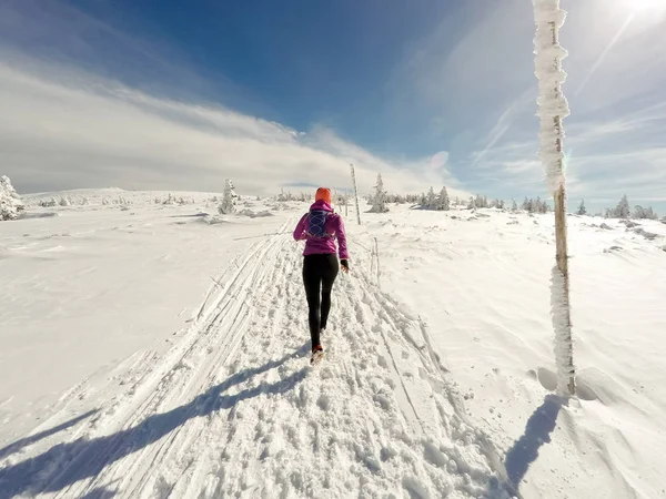 Futó nő a téli nyomvonal, a hó és a fehér-hegységben — Stock Fotó