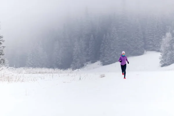 Trail running girl in winter mountains