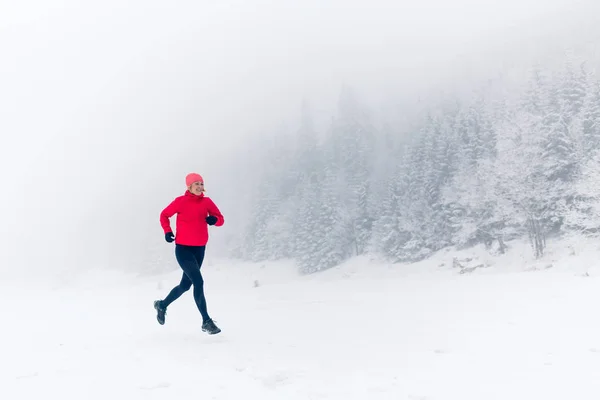 Mujer corriendo en la nieve en las montañas de invierno — Foto de Stock