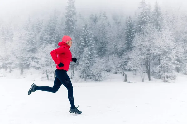 Chica corriendo en la nieve en las montañas de invierno — Foto de Stock