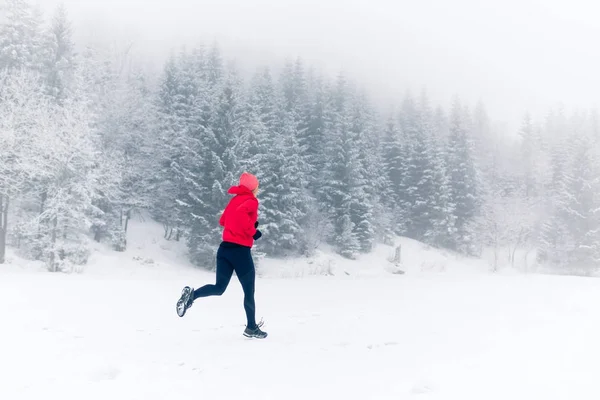 Woman running on snow in winter mountains