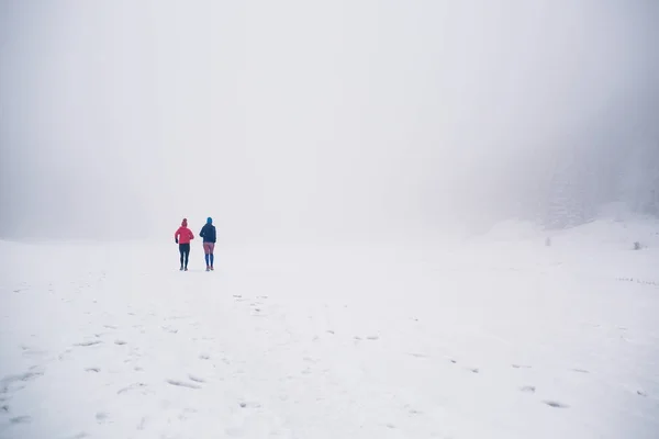 Dwie kobiety biegania na śniegu w górach zimą — Zdjęcie stockowe