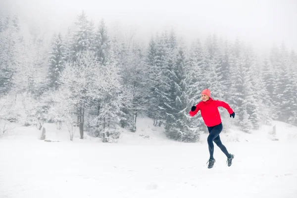 Woman trail running on snow in winter mountains — Stock Photo, Image