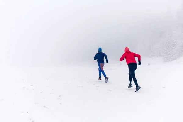 Дві жінки біжать на снігу в зимових горах — стокове фото