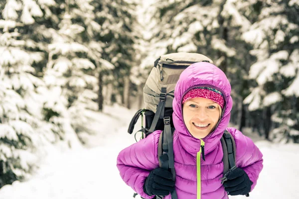 Happy woman walking in winter forest with backpack — Stock Photo, Image