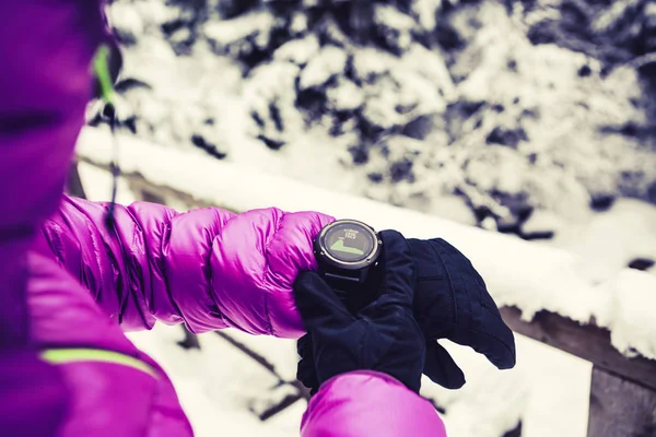 Mulher caminhante verificando esportes assistir em florestas de inverno e montanhas — Fotografia de Stock