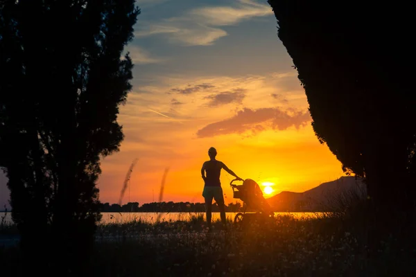 Mutter mit Baby im Kinderwagen genießt Mutterschaft bei Sonnenuntergang — Stockfoto