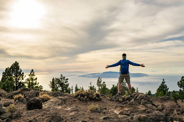 Homem comemorando o pôr do sol olhando para a vista nas montanhas — Fotografia de Stock