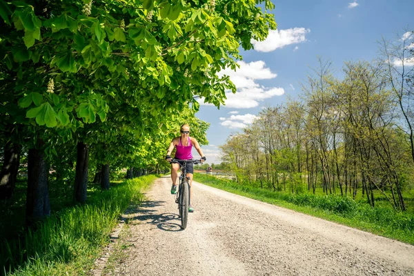Woman cycling a mountain bike in city park, summer day — Stock Photo, Image