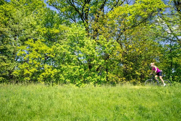 Kvinna som cykling en mountainbike i stadsparken, sommardag — Stockfoto