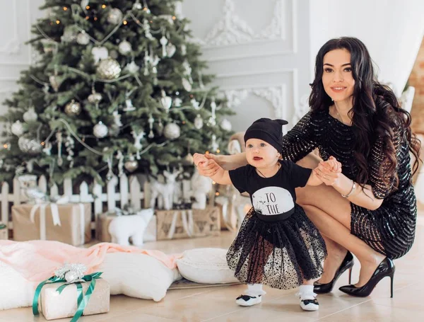 Meisje van de baby en de moeder in de buurt van de kerstboom — Stockfoto