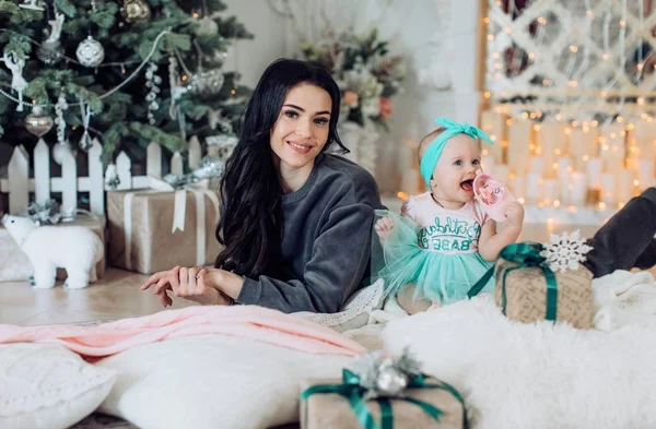 Meisje van de baby en de moeder in de buurt van de kerstboom — Stockfoto