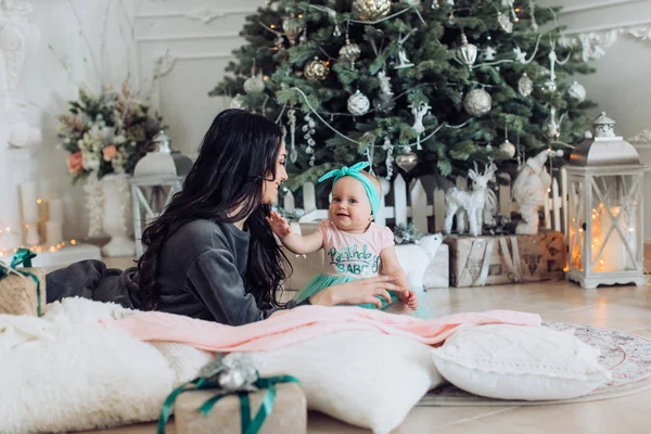 Meisje van de baby en de moeder in de buurt van de kerstboom — Stockfoto