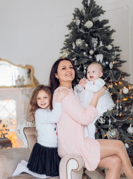 Kleine meisjes en moeder in de buurt van de kerstboom — Stockfoto