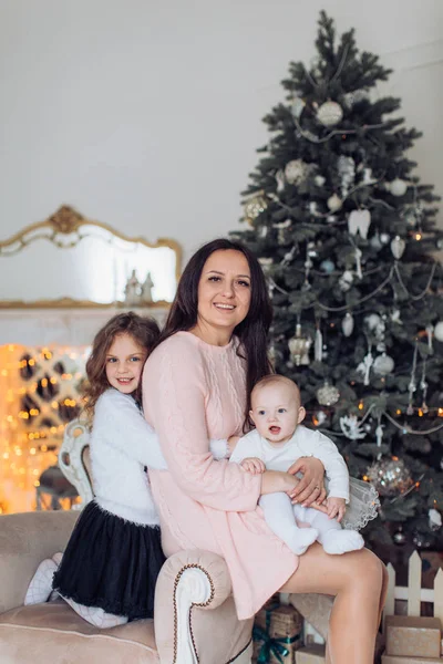 Kleine meisjes en moeder in de buurt van de kerstboom — Stockfoto