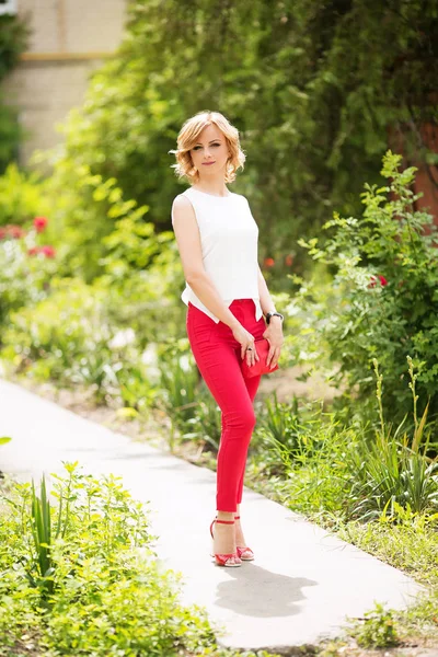 Blond woman   posing in red pants — Stock Photo, Image