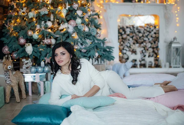 Beautiful  woman near Christmas tree posing in studio