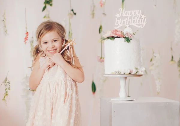 Cute little girl in dress with cake at home, happy childhood concept