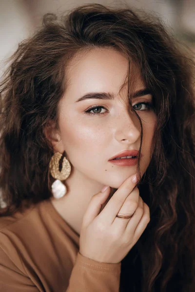 Alnında üst ve küpeleri olan güzel genç bir kadın.