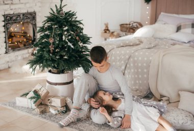 Mutlu çocuklar noel arifesinde Noel ağacının yanında poz veriyorlar.