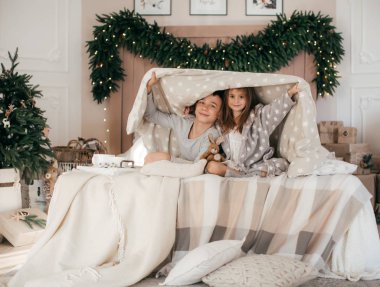 Mutlu çocuklar Noel 'de poz veriyorlar. İç kısımda, yatakta.