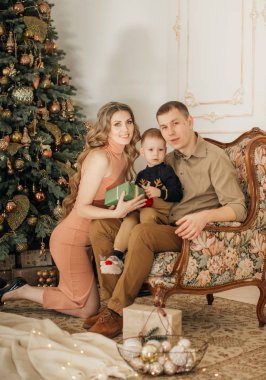 Noel arifesinde anne babası poz veren sevimli küçük bir çocuk. 