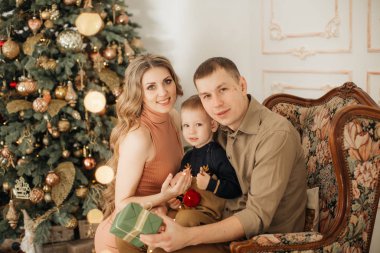 Noel arifesinde anne babası poz veren sevimli küçük bir çocuk. 