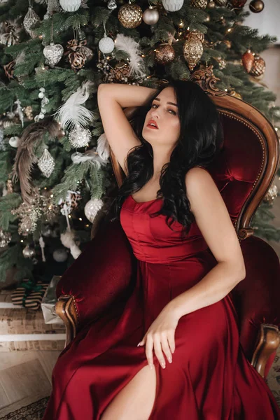 美しいです女性で赤いドレスポーズ近くクリスマスツリー — ストック写真