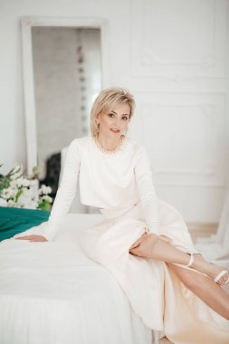 Stüdyoda beyaz elbiseli güzel sarışın bir kadının portresi.