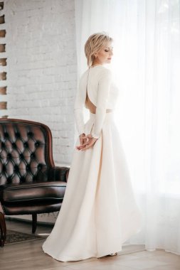 Stüdyoda beyaz elbiseli güzel sarışın bir kadının portresi.