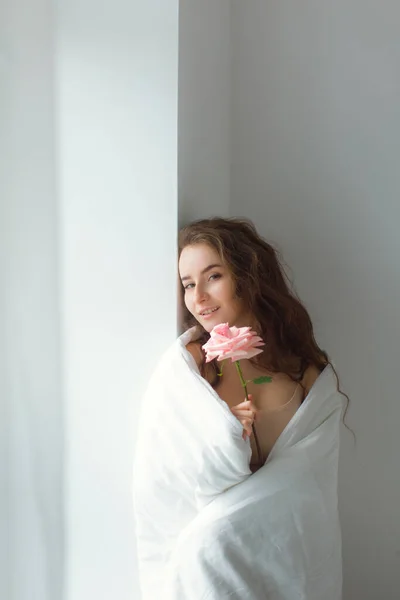 Foto Stock Niña Bajo Las Cubiertas Blancas Sosteniendo Rosa Rosa —  Fotos de Stock