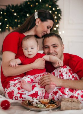 Noel arifesinde anne babası poz veren sevimli küçük bir çocuk.  