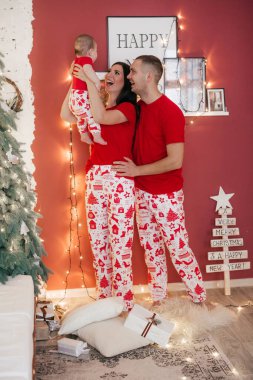 Noel arifesinde anne babası poz veren sevimli küçük bir çocuk.  