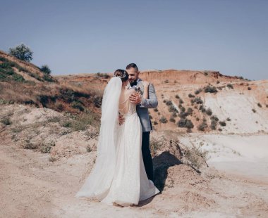 Güzel ve genç gelin ve damat dışarıda poz veriyor.