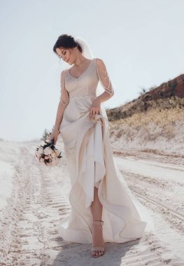 Beyaz gelinlikli güzel gelin dışarıda poz veriyor.