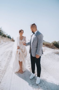 Güzel ve genç gelin ve damat dışarıda poz veriyor.