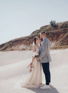 Güzel ve genç gelin ve damat dışarıda poz veriyor.